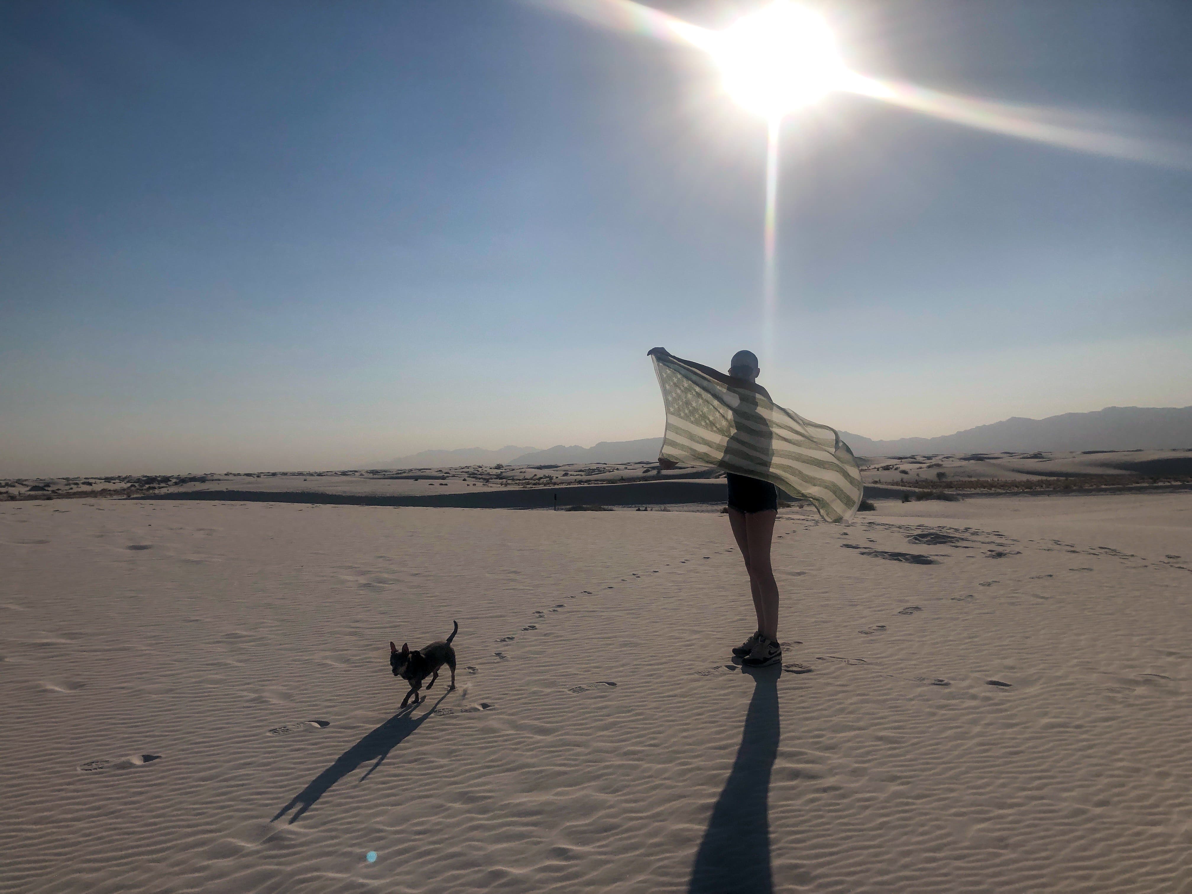 Translucent currency flag held in a desert landscape.