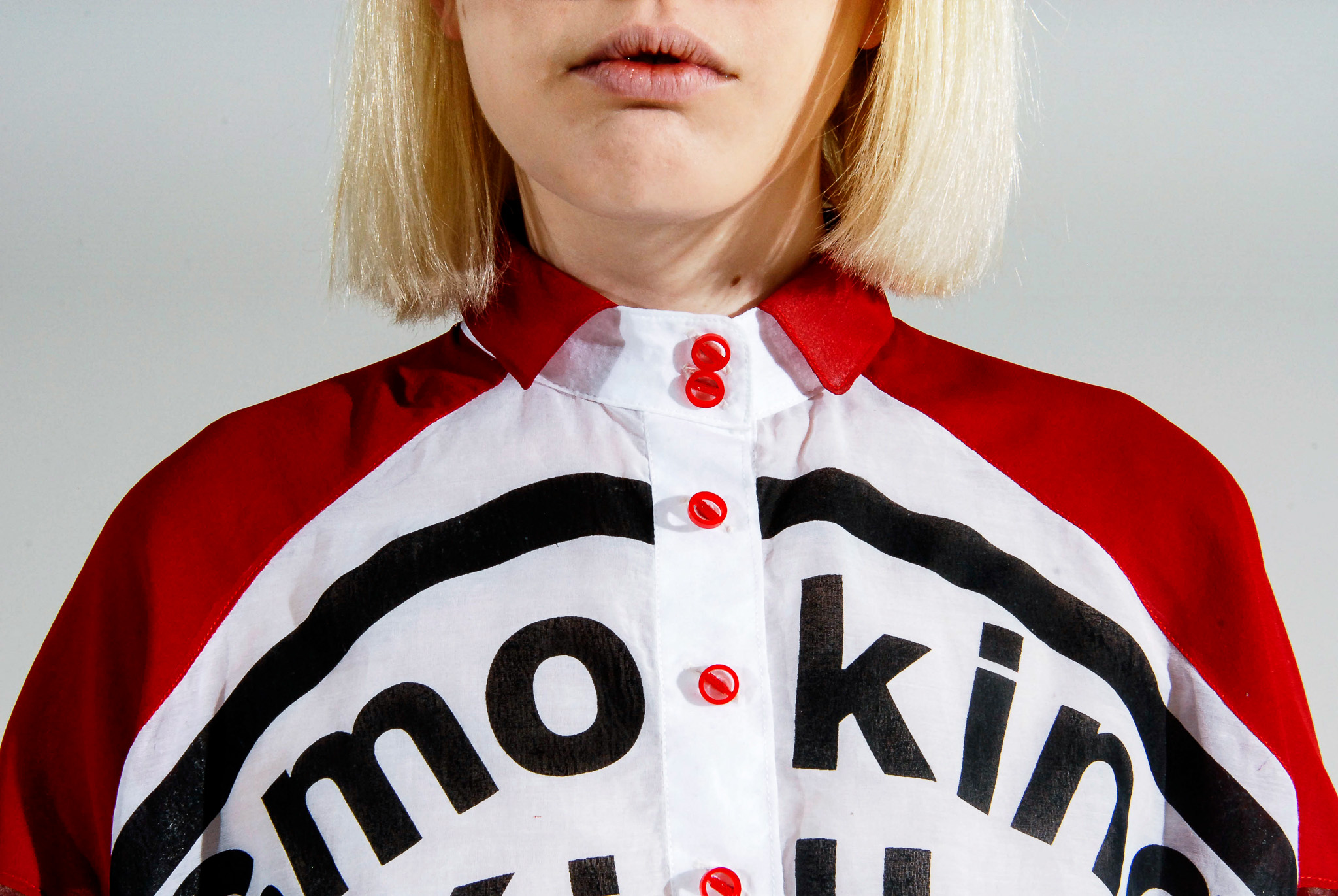Close view of a model wearing white sunglasses and a red, white, and black Smoking Kills crop top.